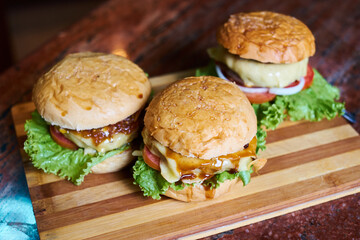 Assortment of Gourmet Cheeseburgers on Wooden Board – Fresh Homemade Fast Food Concept