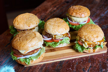 Assortment of Gourmet Cheeseburgers on Wooden Board – Fresh Homemade Fast Food Concept