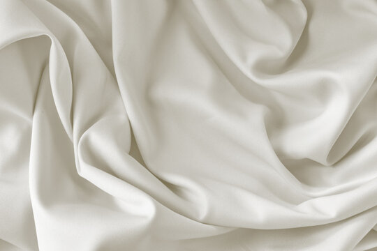 Cloud dancer toned silk fabric background with folds. Copy space. Monochrome background 2026 color.