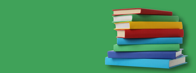 Colorful books stacked on green backdrop for study or mockup