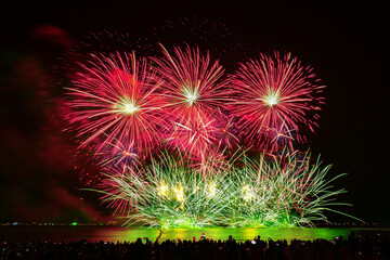 Colorful fireworks celebration and the night sky background with crowded people on the beach.