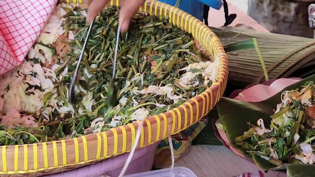 Fresh pecel vegetables prepared by hand at Indonesian street stall. Traditional pecel vegetable preparation in local street food scene. Indonesian pecel making process with fresh greens close up
