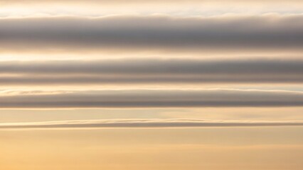 Horizontal layered cloud bands at sunset, representing atmospheric stratification and stable weather patterns.