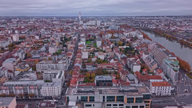 Drone advances over Alfortville rooftops with Seine River along the city edge.
