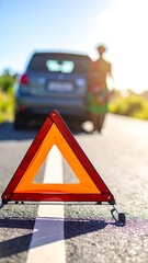 A red warning triangle sits on a road near a car and a person