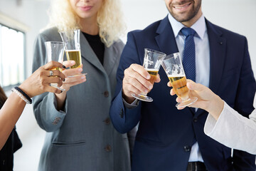 close up businesspeople clinking glasses and celebrating have a drink after work in the office