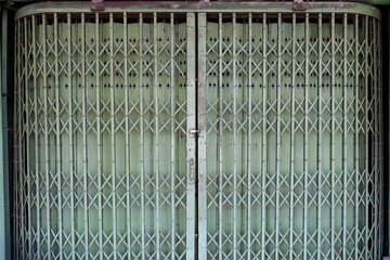 Old and dirty green steel folding slide door with padlock background
