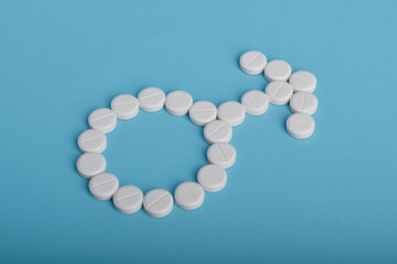 Male gender sign made from medical pills on blue background. Men’s health, fertility, treatment, and healthcare concept.