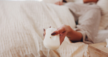 Electric blanket, remote and hands in house with setting, heat bedding and comfort level in...