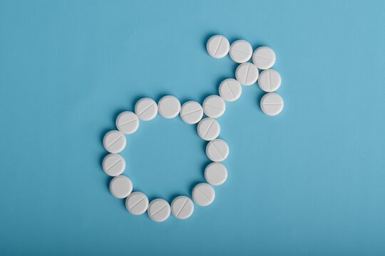 Male gender sign made from medical pills on blue background. Men&rsquo;s health, fertility, treatment, and healthcare concept.