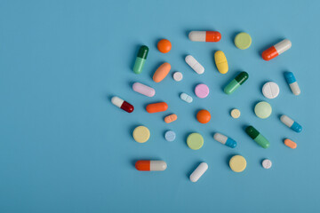 Various colorful pills and capsules on blue background, displaying various medicines, vitamins and...