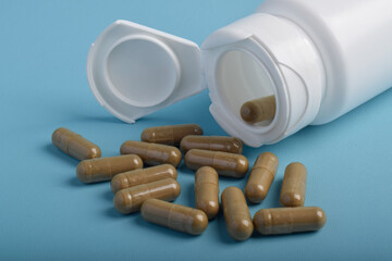 Capsules spilling from a bottle on a blue background. Healthcare and pharmacy. Medical treatment...