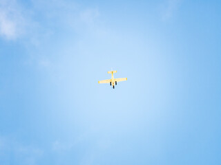 Small ultralight airplane with overhead wing and single propeller flying in sunset sky.