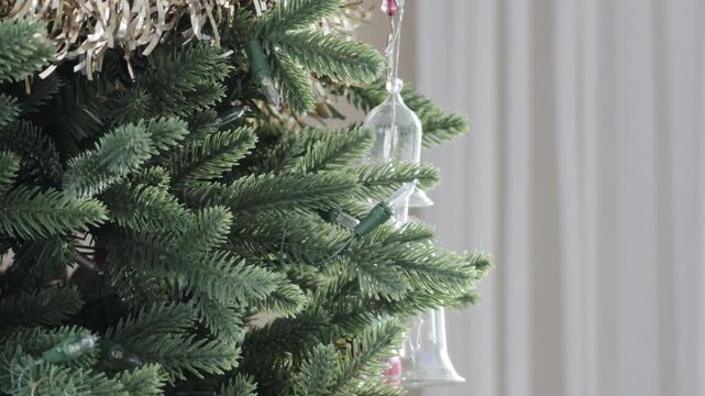 A close up of a hand reaching into frame and taking a bright red ornament off of the decorated tree.