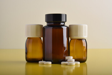 Medical bottles and pills isolated on yellow background. Concept of medical treatment supplies.