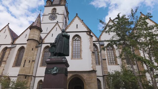 Scenic view of the Lutheran Cathedral of Saint Mary in Sibiu, featuring the statue of Bishop Georg Daniel Teutsch in the foreground.