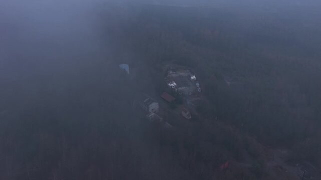 Abandoned mansions and houses in the middle of dense forests in cold, foggy weather. The horror atmosphere evokes fear from the drone's perspective.