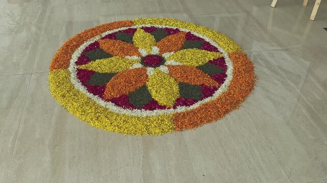 Camera circles around a vibrant flower-petal rangoli arranged in a colorful symmetrical pattern on a polished floor, highlighting festive detail and texture.