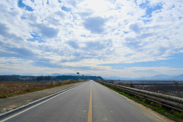 Fototapeta premium An endless stretch of road under a cloudy blue sky