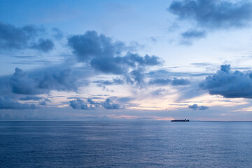 Container ship with lights on at sunset