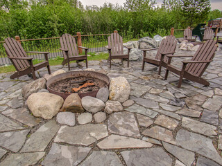Adirondack wooden chairs around  a fire pit.