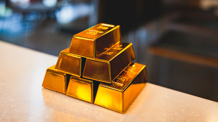 Stacked gold bars on table with blurred background, representing wealth, financial security, investment asset, inflation hedge, precious metal reserve, and long-term capital preservation concept.