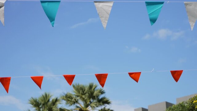 Tropical party bunting decorations for outdoor kids celebration. Cinematic walking motion under triangular flags 