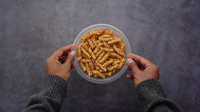 Hands holding a plate of corkscrew pasta