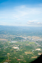 Obraz premium Stunning aerial view of lush green landscape and distant mountains under a clear blue sky.