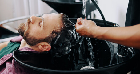 Hands, man and washing hair at barbershop with water, basin and grooming services at salon. People, shampoo and conditioner for hygiene, product and growth benefits with customer experience at store
