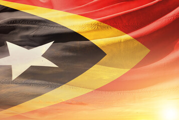 East Timor national flag waving in sunny sky with beautiful sunset. East Timor national flag for...