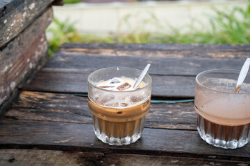 Two glasses of iced coffee on a rustic wooden table, evoking a relaxed cafe atmosphere.