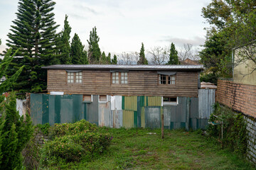 A weathered wooden house with a patchwork fence in a serene outdoor setting.