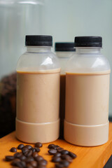 Iced Ready-to-Drink (RTD) Bottled Milk Coffee with Coffee Beans on Wooden Table - Contemporary Refreshing Beverage