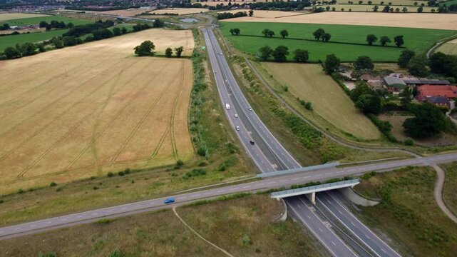 Drone footage captures vehicle travelling along a Norfolk dual carriageway. This high footage starts at a bridge going over the Broadland Northway then moves along the road with some vehicle.