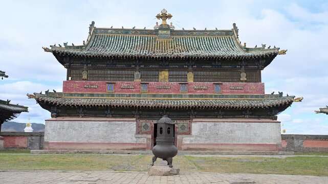 Ornate temple pavilion at Erdene Zuu Monastery, Mongolia. A golden Dharma Wheel and deer sculptures sit atop green tiled eaves, showcasing the artistry of the country's oldest religious site.