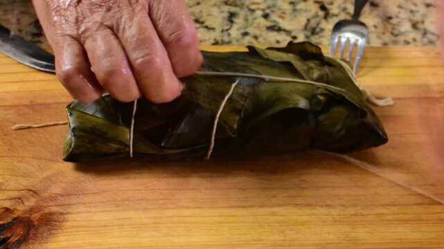 Authentic close-up showing the full process of unwrapping the banana leaf from a Hallaca, perfectly ready-to-eat for a Christmas recipe video