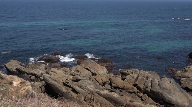 A phenomenal view of the sea water with an amazing rock formation. The waves are rather calm and the water is clear with a touch of dark blue.