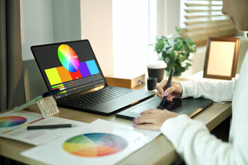 Close up of a graphic designer using a digital drawing tablet while creating artwork on a computer