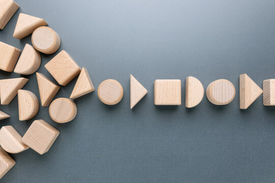 Scattered wooden geometric blocks gradually forming an organized single-line flow, symbolizing teamwork, alignment, system optimization, and the transformation from chaos to order in business process