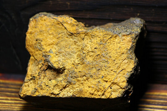 Rough yellow limonite iron ore specimen from Kaluga region, Russia, showcasing a textured mineral surface against a dark backdrop