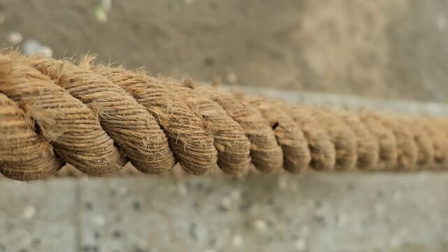 Close up slow motion tracking shot of thick natural fiber rope showing detailed texture and tight weave suitable for projects related to strength industry or crafts