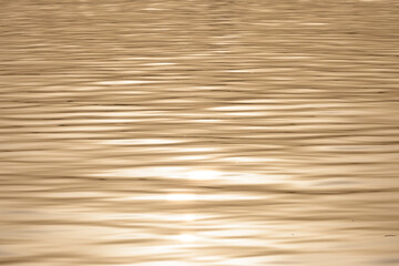 Golden water surface with rippling waves and light reflection