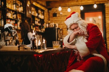 Santa claus looking tired at a dark bar