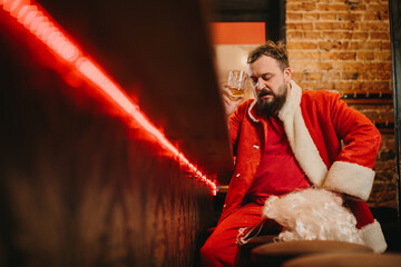 Stressed santa drinking alcohol at dimly lit bar