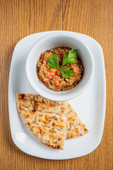 Delicious eggplant dip garnished with herbs served alongside warm, grilled flatbread