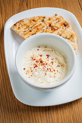 Freshly prepared creamy dip garnished with red pepper flakes, paired with warm flatbread