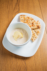 Rich, creamy dip accompanied by warm flatbread on a rustic wooden surface, perfect for sharing
