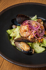 A vibrant seafood salad features shrimp, mussels, and crisp greens topped with sliced onions