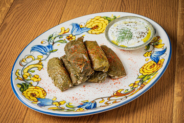 Tasty rolled grape leaves filled with rice and spices, served alongside cooling yogurt sauce